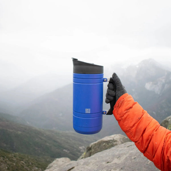 man holding a flask outside on a hike