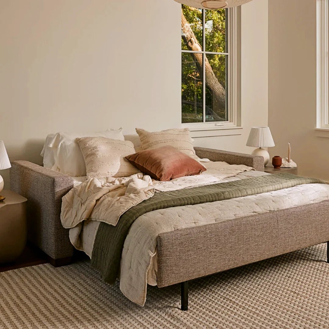 American Leather Lyons Silver Sleeper Sofa opened up with pillows in a white room. - DIGS