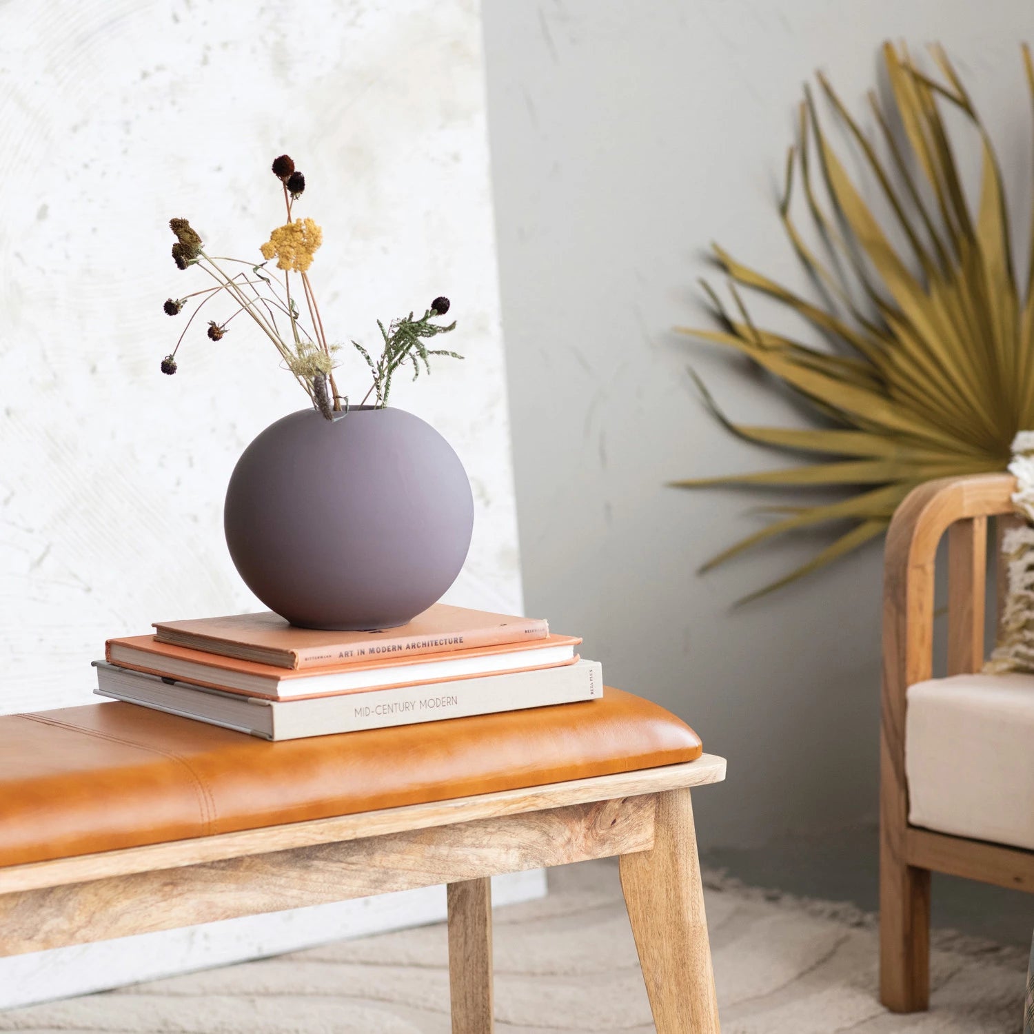 Round Matte Plum Vase with flowers and placed on top books on a table