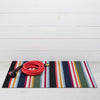 Striped doormat with a coiled red garden hose on a white wooden floor