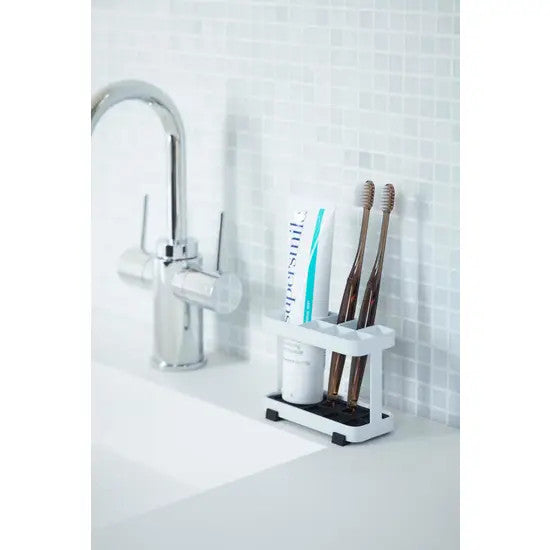tooth brush stand with toothbrushes beside a faucet