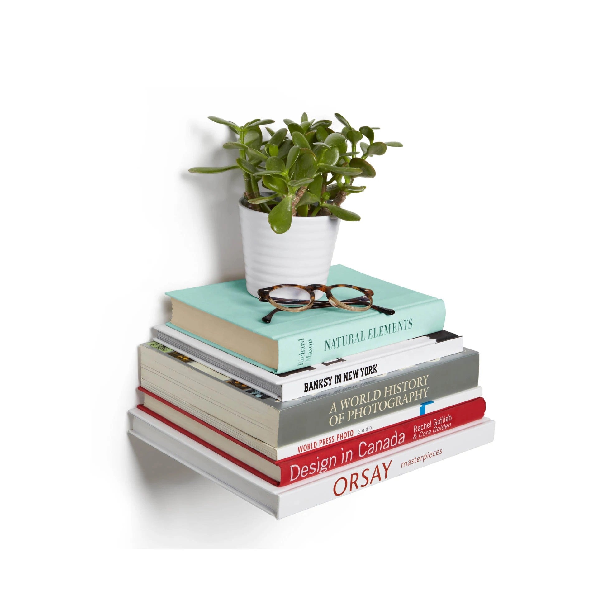 Umbra Conceal Floating Bookshelf with books, glasses, and a potted plant on it